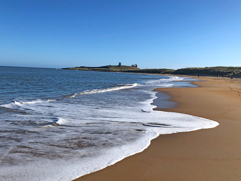 Walking along the beach looking towards Dunstanburgh Castle