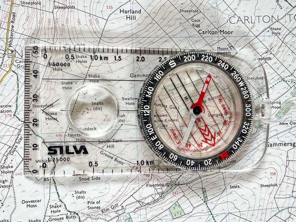 A compass sat on a map, with the red compass arrow pointing towards Magnetic North