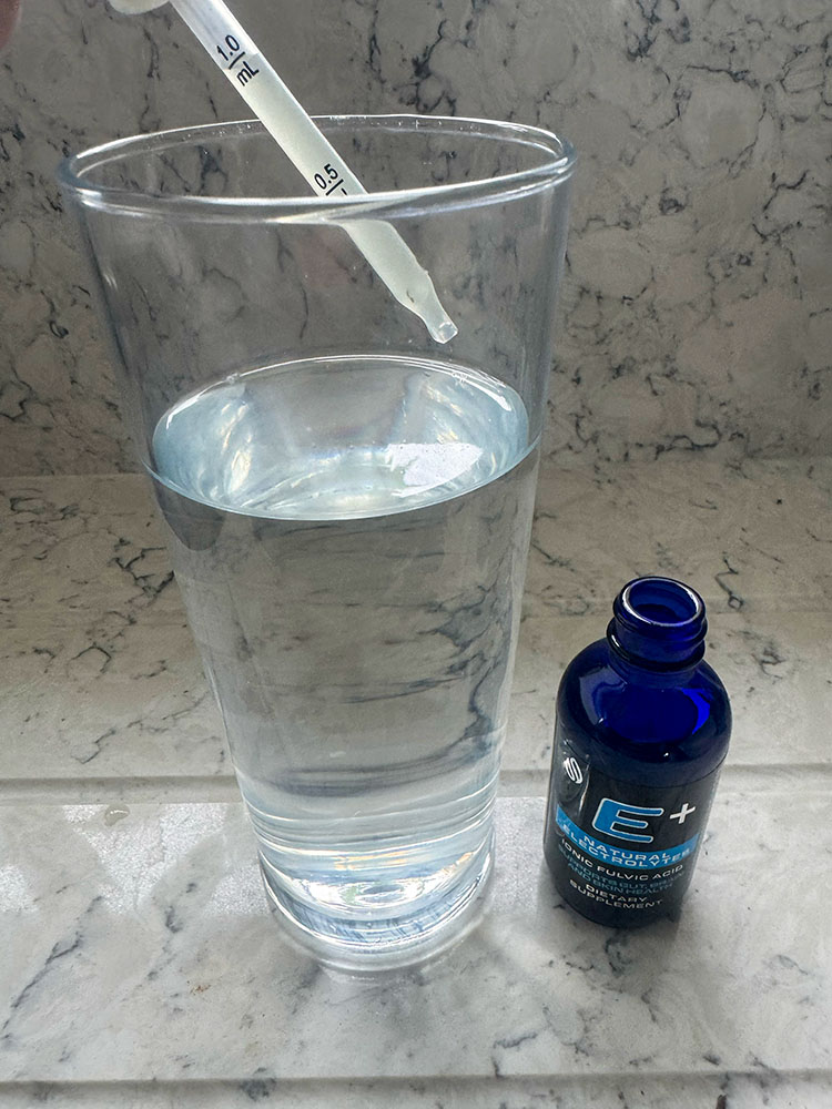 One ml of Optimal Hydrations OH-E+ Natural Electrolytes is being put into a glass of water