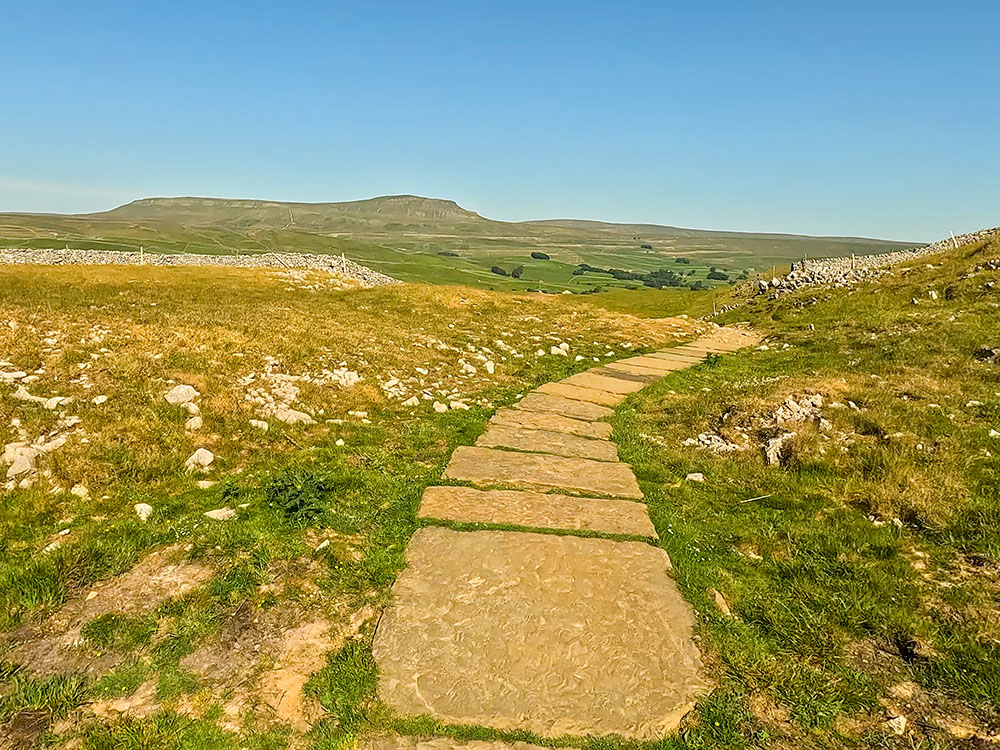 Flagged path on the Yorkshire 3 Peaks walk heading back to Horton in Ribblesdale, with Pen-y-ghent ahead