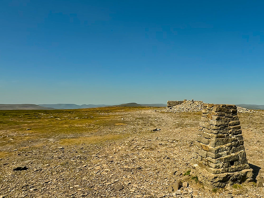 Trig point and weather shelter on the summit of Ingleborough, looking towards Whernside and the Howgills