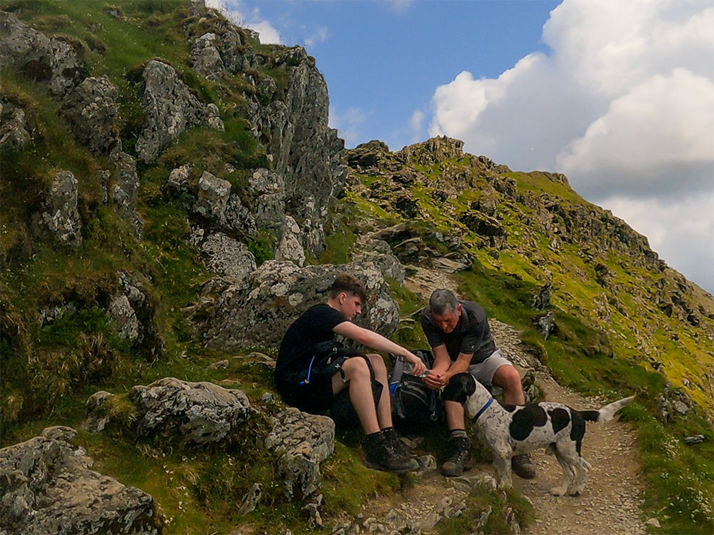 Mick and Dominic pouring some water out for Alfie their dog to drink on a warm, sunny day