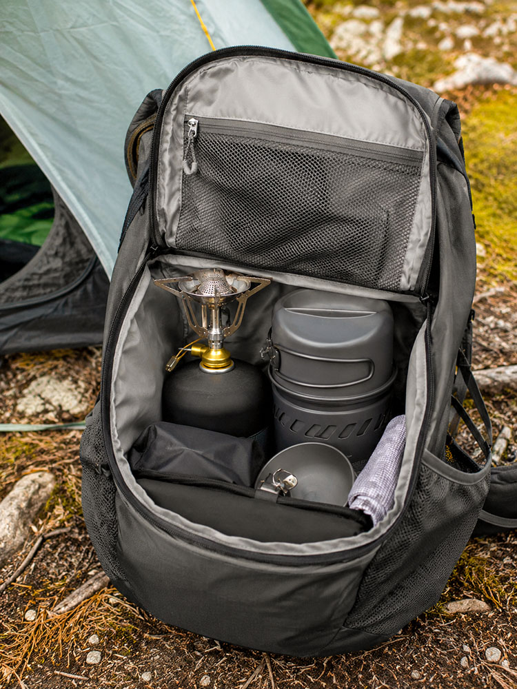 Open backpack packed with a lightweight camping stove, fuel canister and cook kit, showing how compact stove gear fits in a hiking pack.