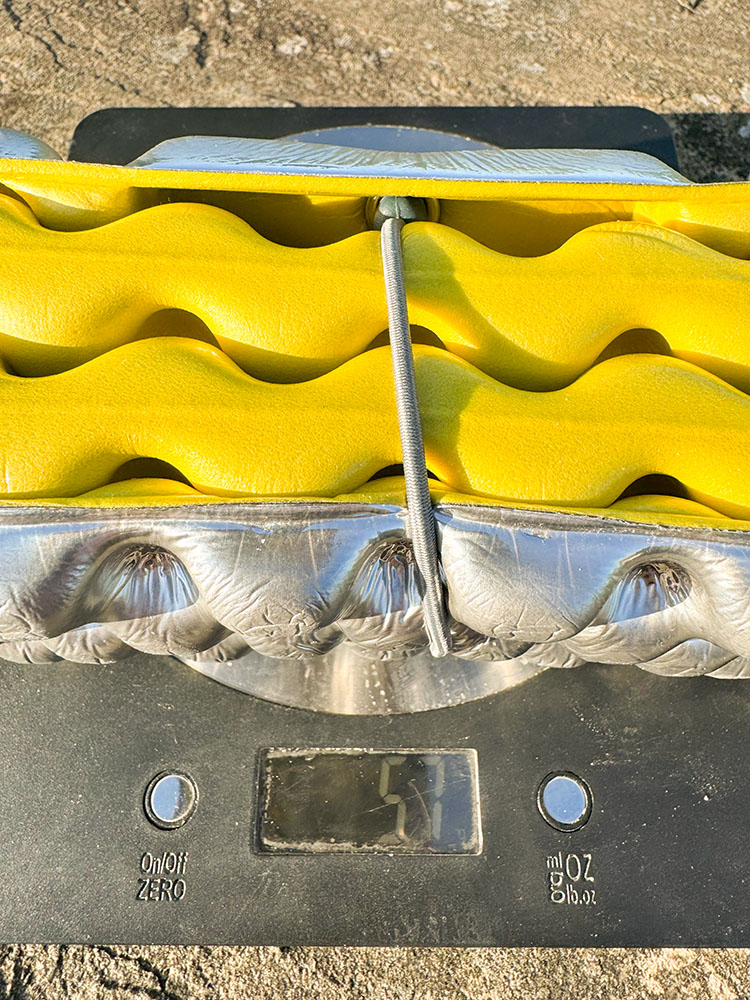 Digital scale showing a folded Therm-a-Rest Z Seat cushion weighing 57 grams.