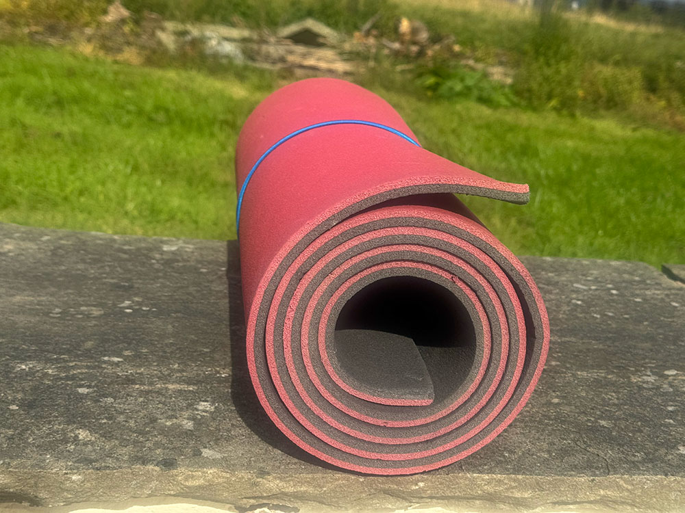 A rolled-up closed-cell foam sleeping mat