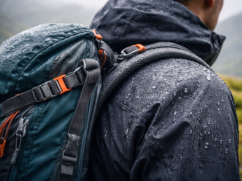 Close view of rucksack straps pressing on the shoulders of a waterproof jacket in wet weather