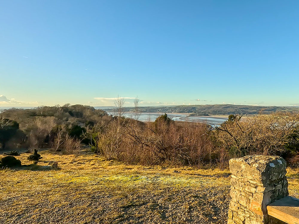 View across to Grange-Over-Sands and out towards Morecambe Bay from the stone and wooden bench on Arnside Knott