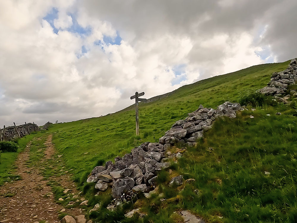 Malham footpath sign pointing up the hill