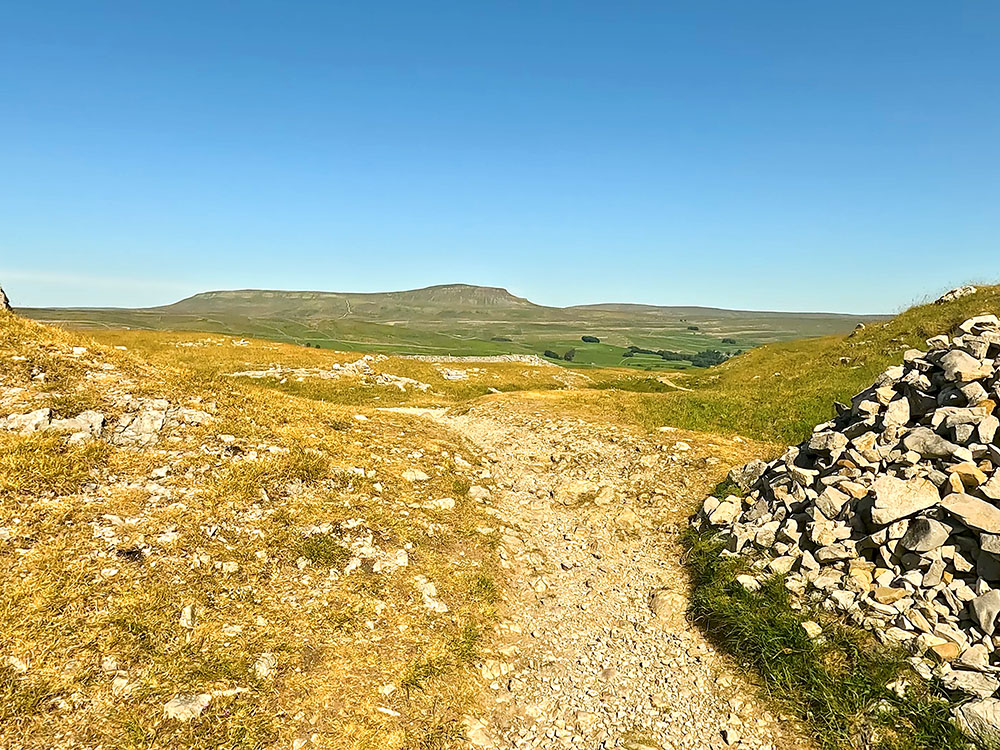 The footpath passing by a cairn at Sulber Nick with Pen-y-ghent on the horizon