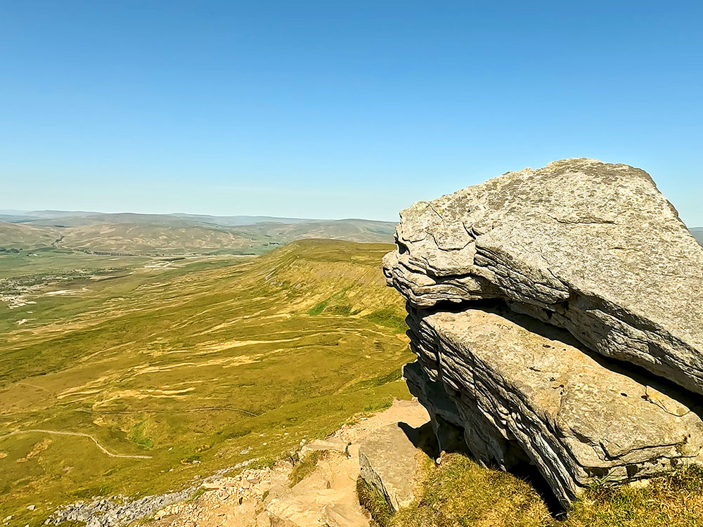 The path passes by the large boulder with Ribblehead Viaduct in the distance