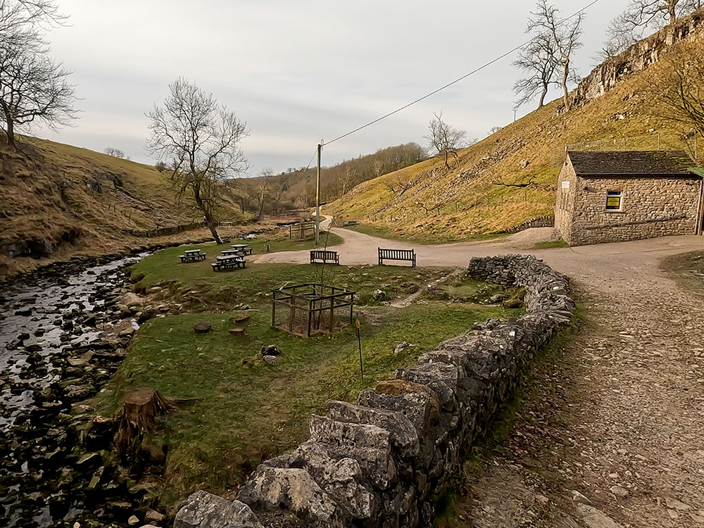 Clapham Beck and picnic tables in front of Ingleborough Cave