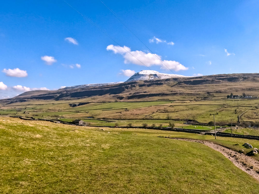 The Ingleton Waterfalls path heading down towards Oddie's Lane with the snow-capped Ingleborough on the horizon ahead