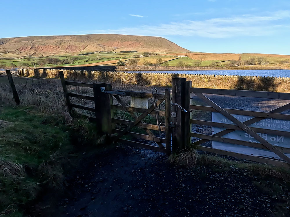 Gate out of the Pendle Sculpture Trail looking across Upper Black Moss Reservoir to Pendle Hill