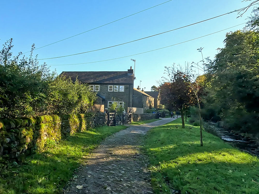 The path alongside Pendle Water approaching houses at White Hough on the Pendle Witches Walk