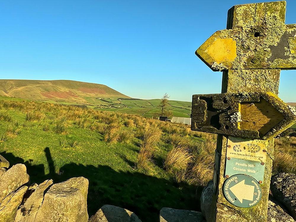 Looking back over the wall towards Pendle Hill from the Pendle Way footpath sign