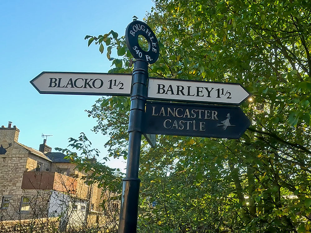 The road sign in Roughlee, also including the witches' sign to Lancaster Castle