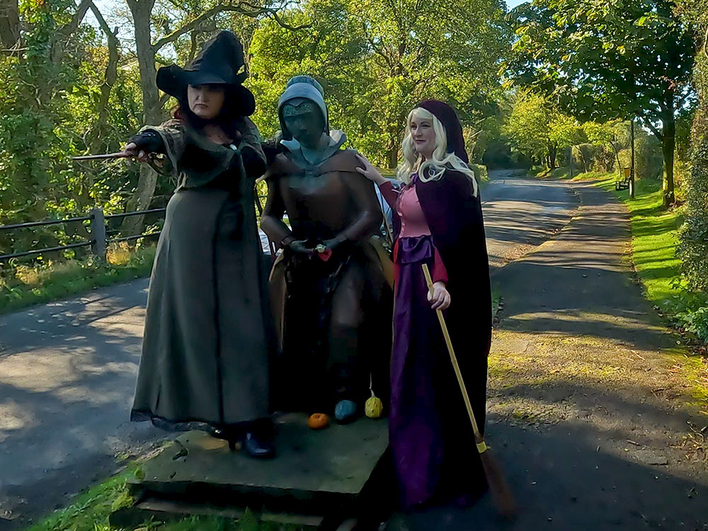 Two 'Peaky Blinders' witches standing by the Alice Nutter statue