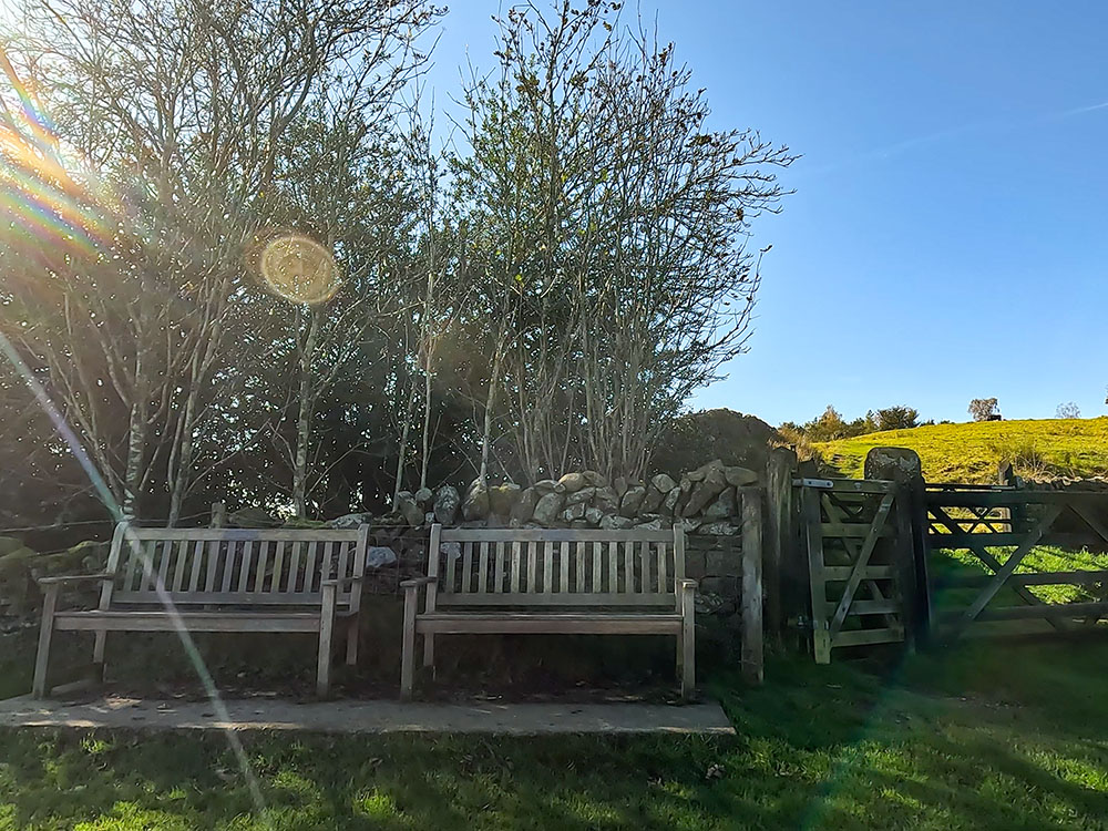 Two wooden benches by the gate that leads through onto Heys Lane