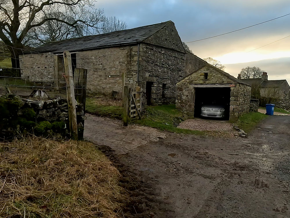 Approaching the buildings and footpath sign at Brackenbottom