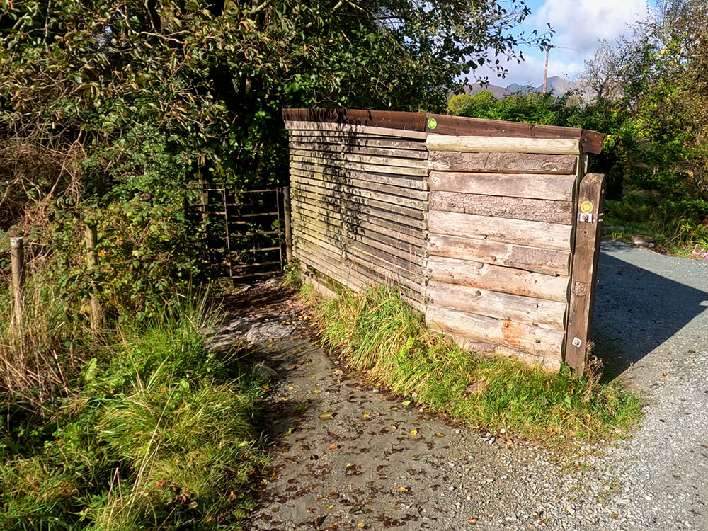 Yellow footpath sign pointing the way through the metal kissing gate