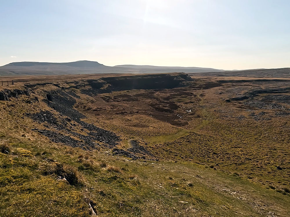 Path heading down onto Thieves Moss and limestone pavement with Pen-y-ghent on the horizon