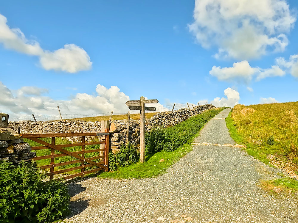 4-way signpost where the Pennine Way heads left down Horton Scar Lane and the 3 Peaks path keeps straight on towards Whitber Hill