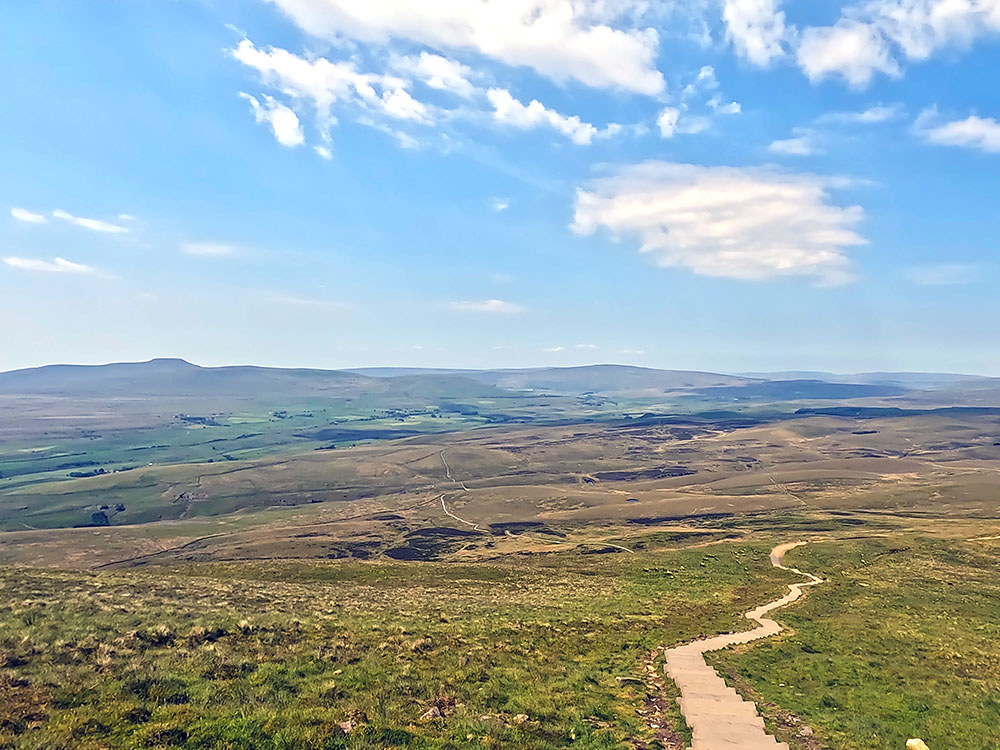 Steps heading down from Pen-y-ghent summit with Ingleborough and Whernside ahead on the horizon