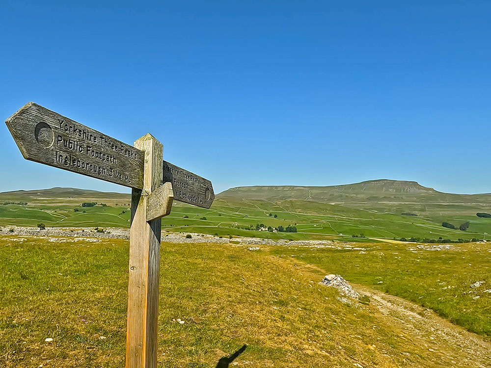 Yorkshire Three Peaks footpath sign to Horton in Ribblesdale pointing towards Pen-y-ghent on the horizon