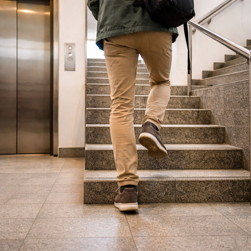 A rear view of a person choosing stairs instead of a lift