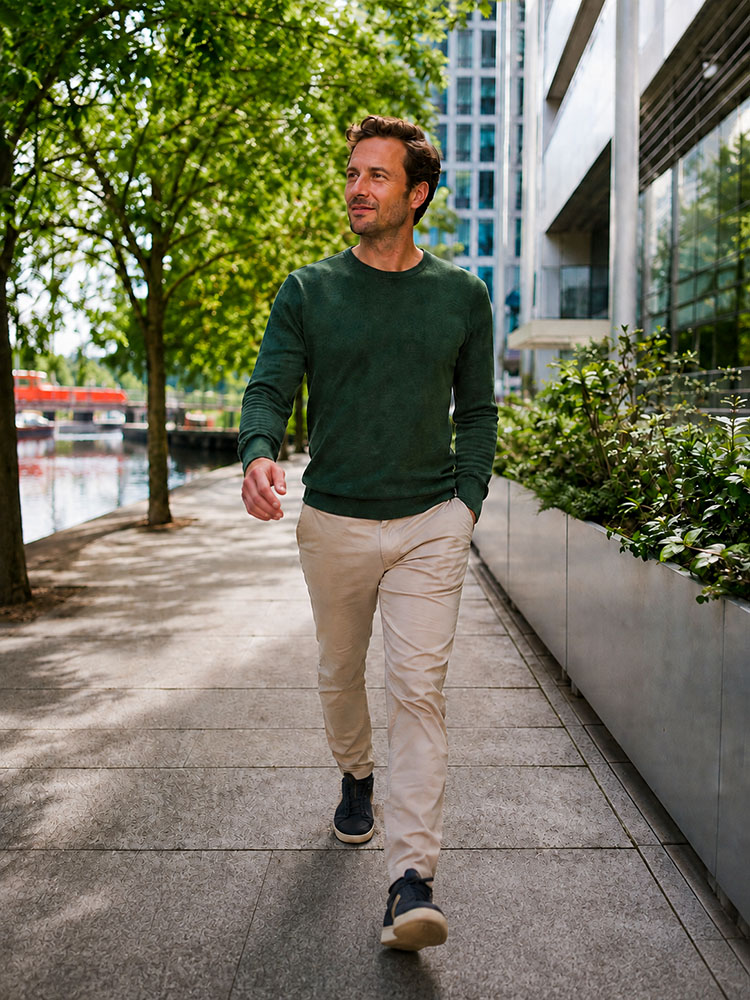 A man in smart-casual clothing taking a brisk walking break beside an urban canal and modern offices in the UK.